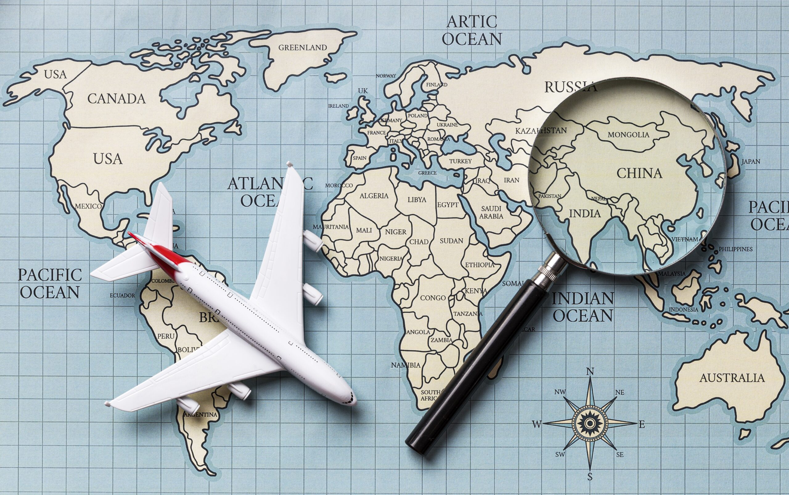 A map with a model airplane and magnifying glass on top